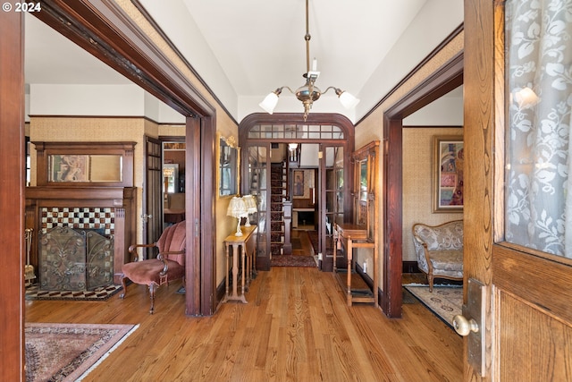 entryway with a tiled fireplace, light hardwood / wood-style flooring, and an inviting chandelier