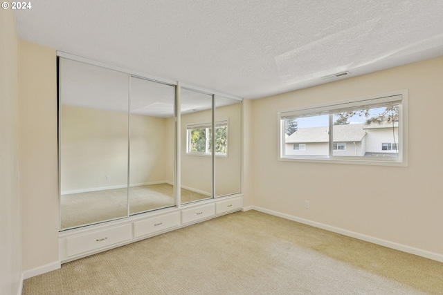 unfurnished bedroom with light carpet and a textured ceiling