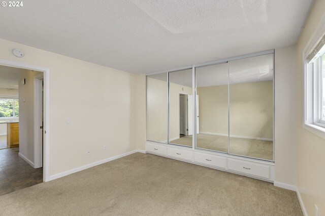 unfurnished bedroom with multiple closets, carpet floors, and a textured ceiling