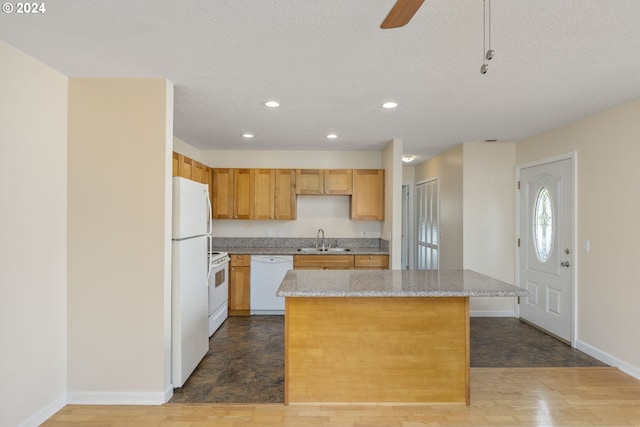 kitchen featuring a textured ceiling, a center island, white appliances, and sink