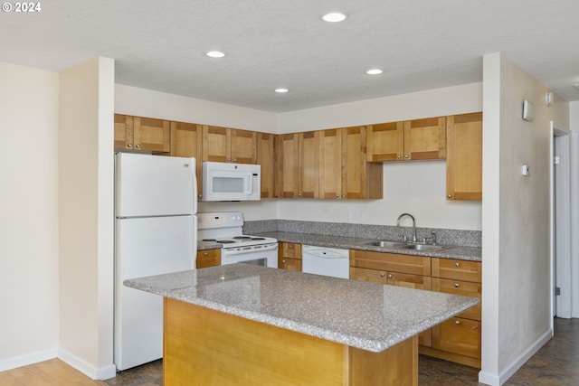 kitchen with light stone countertops, white appliances, a center island, and sink