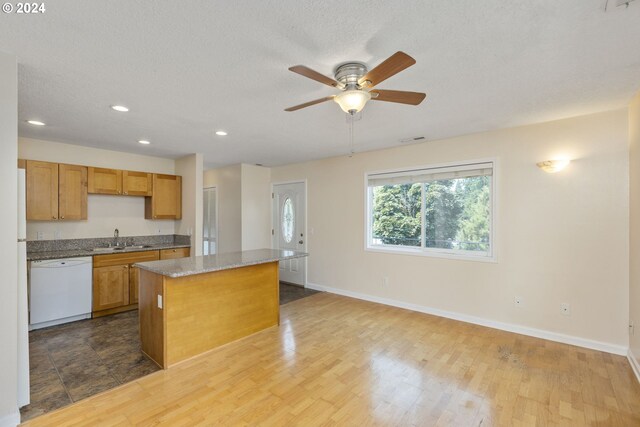 kitchen featuring dishwasher, a center island, sink, hardwood / wood-style flooring, and ceiling fan