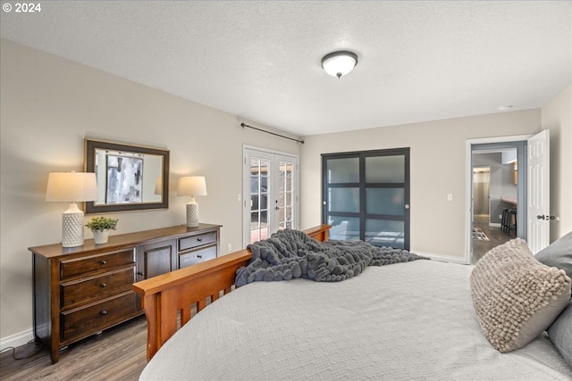 bedroom featuring french doors, wood-type flooring, and a textured ceiling