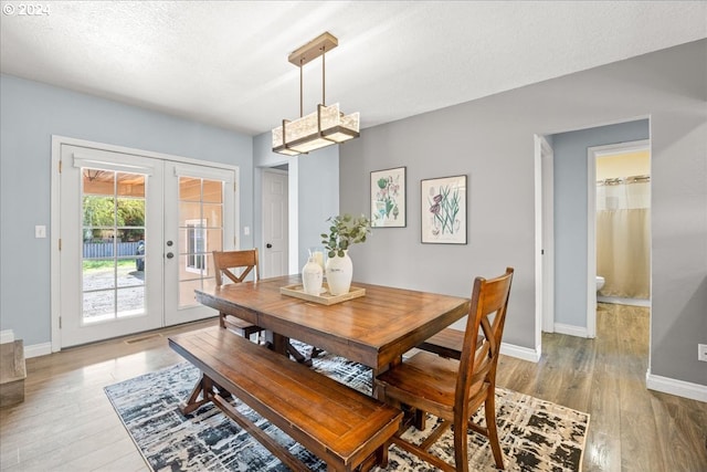 dining area with french doors, a textured ceiling, and wood-type flooring