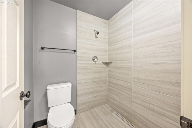 bathroom featuring a tile shower and toilet