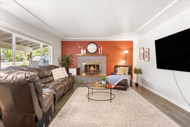 living room featuring a textured ceiling, hardwood / wood-style flooring, and a brick fireplace