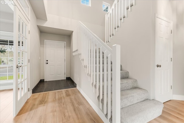 stairs with french doors and wood-type flooring