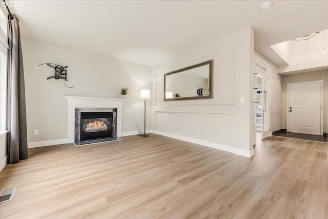 unfurnished living room with a fireplace and light wood-type flooring