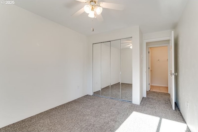 unfurnished bedroom with light colored carpet, a closet, and ceiling fan