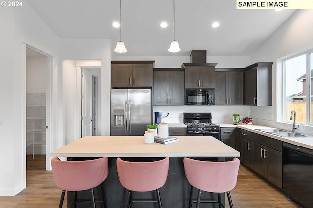 kitchen featuring sink, pendant lighting, a kitchen island, black appliances, and light wood-type flooring