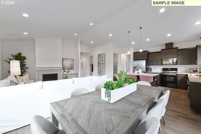 dining space featuring hardwood / wood-style floors, sink, and vaulted ceiling