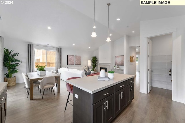 kitchen with a kitchen breakfast bar, high vaulted ceiling, hardwood / wood-style floors, a center island, and hanging light fixtures