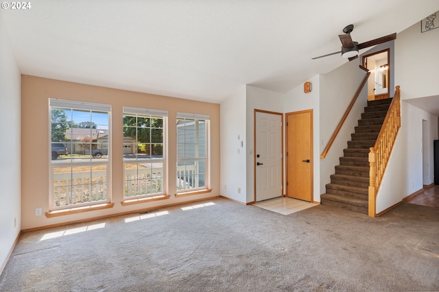 foyer entrance with ceiling fan and light carpet