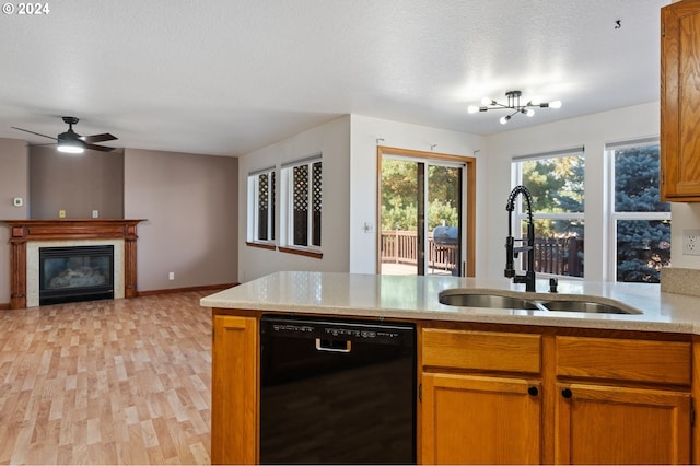 kitchen featuring dishwasher, sink, light hardwood / wood-style flooring, a textured ceiling, and a fireplace