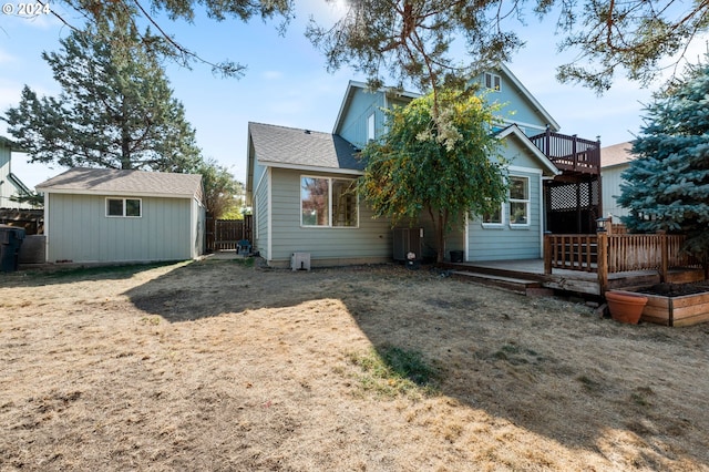 back of house with central air condition unit, a storage unit, and a wooden deck