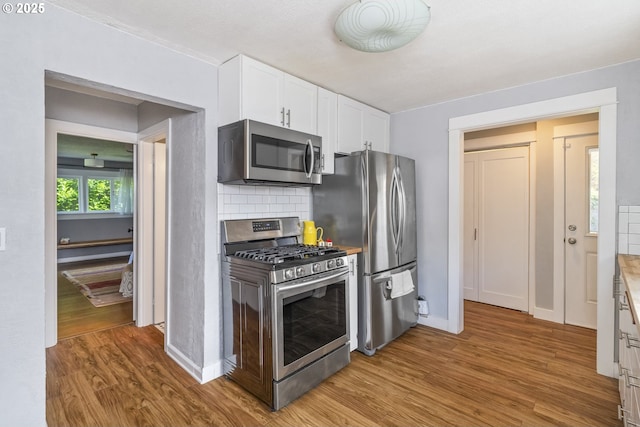 4524 NE 41st Ave, Portland, OR 97211 - kitchen with appliances with stainless steel finishes, light wood-style floors, white cabinets, and backsplash