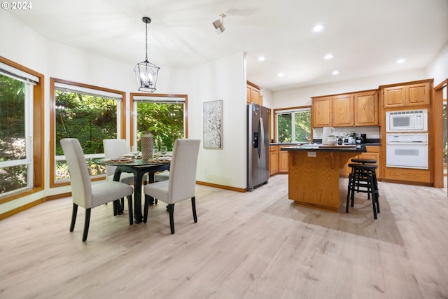 kitchen featuring light wood-type flooring, white appliances, pendant lighting, a chandelier, and a center island