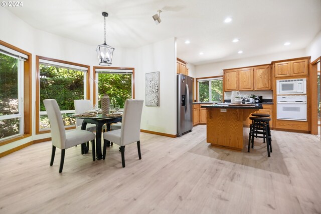 dining space with light hardwood / wood-style floors and a notable chandelier