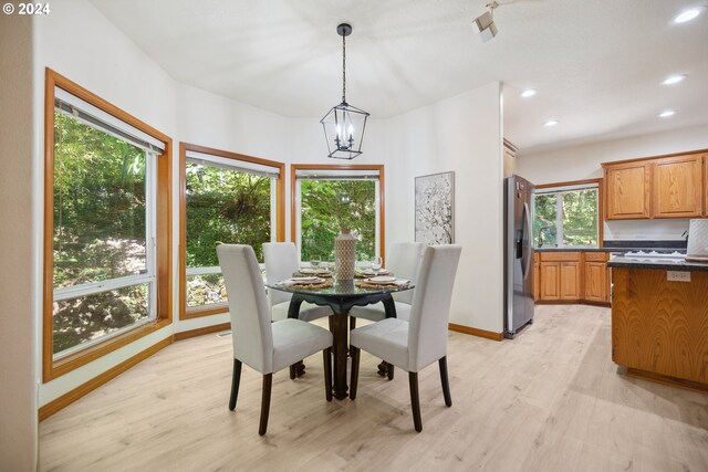 kitchen with a center island, white appliances, light hardwood / wood-style flooring, dark stone countertops, and a breakfast bar area