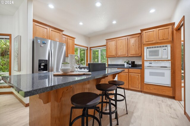 kitchen with a wealth of natural light, stainless steel fridge, a kitchen island, and ceiling fan