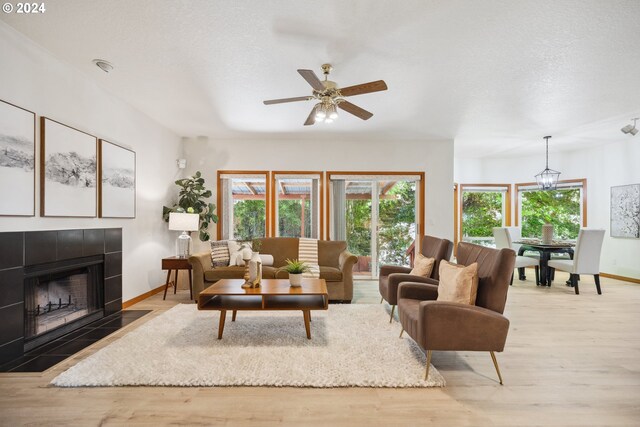 living room with a tile fireplace, light hardwood / wood-style flooring, and ceiling fan