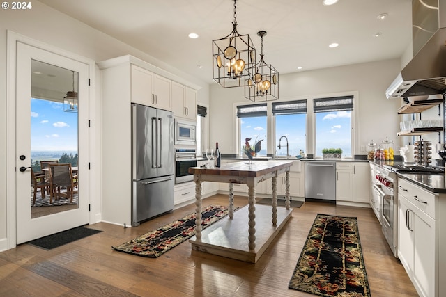 kitchen with recessed lighting, wood finished floors, high end appliances, and wall chimney exhaust hood