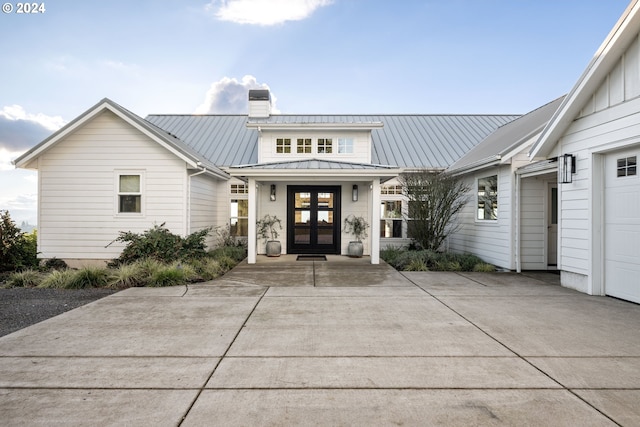 property entrance with french doors, metal roof, a chimney, and a standing seam roof