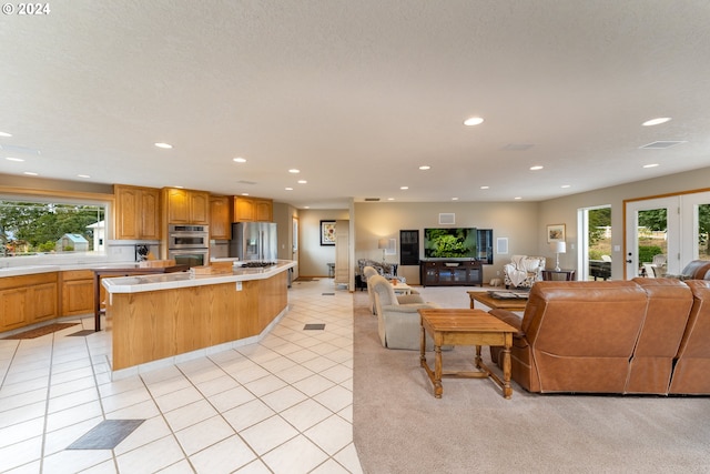 kitchen with appliances with stainless steel finishes, a textured ceiling, a center island, and light tile patterned flooring