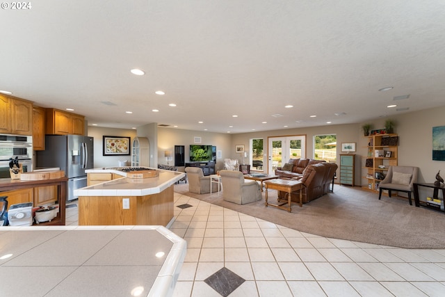 kitchen with a kitchen island, stainless steel appliances, tile countertops, and light tile patterned flooring