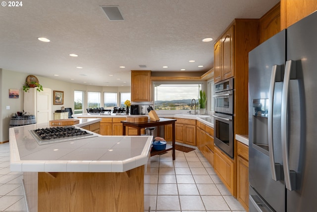 kitchen with a center island, sink, stainless steel appliances, and tile counters