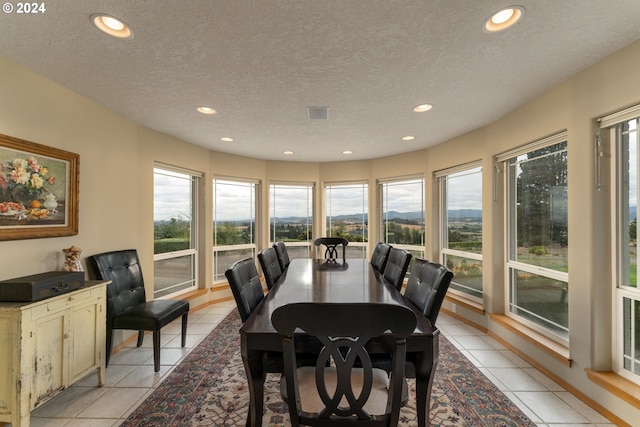 tiled dining area featuring a textured ceiling and a healthy amount of sunlight