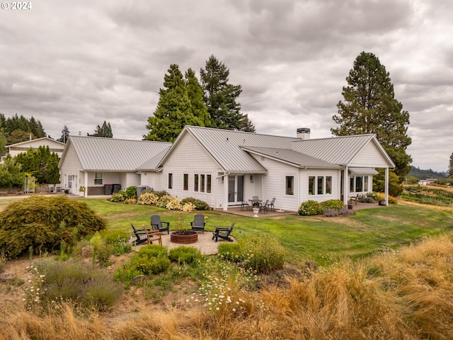 rear view of property with a patio area, a yard, metal roof, and an outdoor fire pit