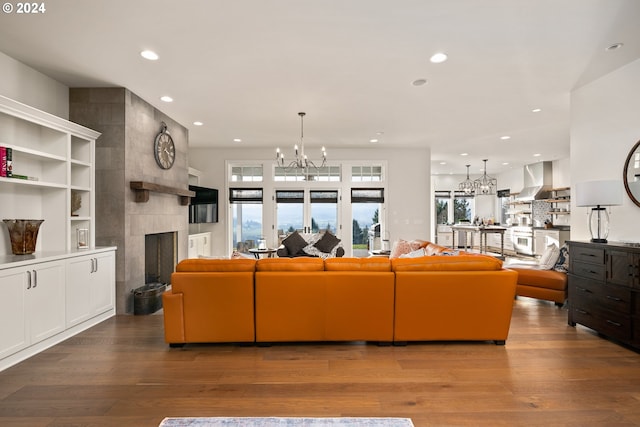 living room featuring wood-type flooring, a tile fireplace, and a chandelier