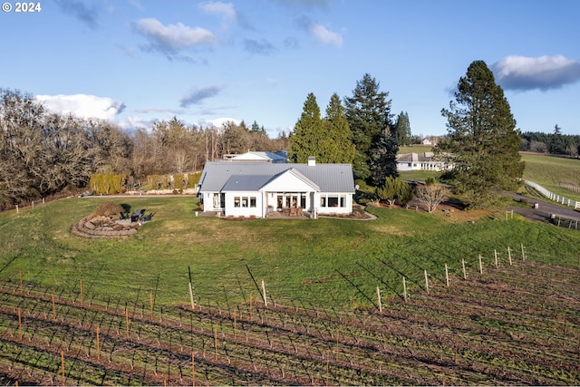 back of house featuring a yard and a rural view