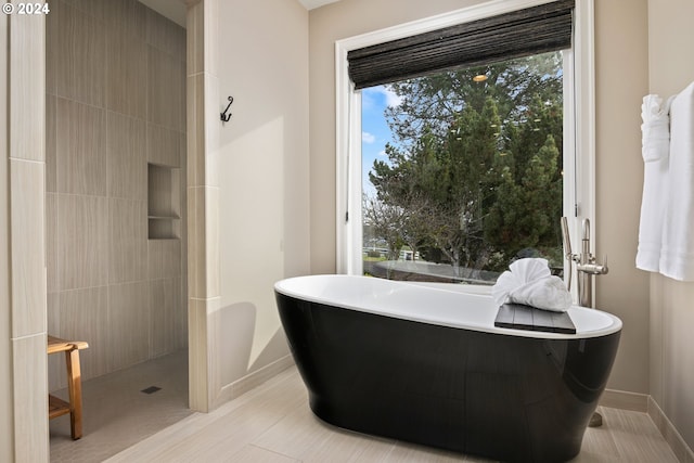 full bathroom with tiled shower, baseboards, and a freestanding bath