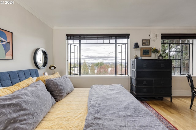 bedroom featuring baseboards, crown molding, and wood finished floors