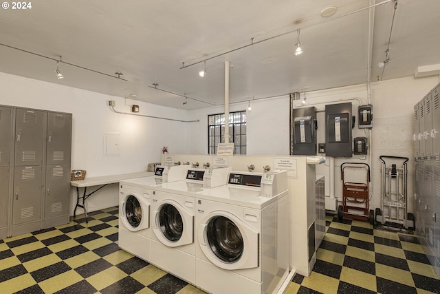 shared laundry area with dark floors, washer and clothes dryer, and electric panel