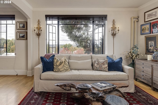 living room featuring arched walkways, ornamental molding, wood finished floors, and baseboards