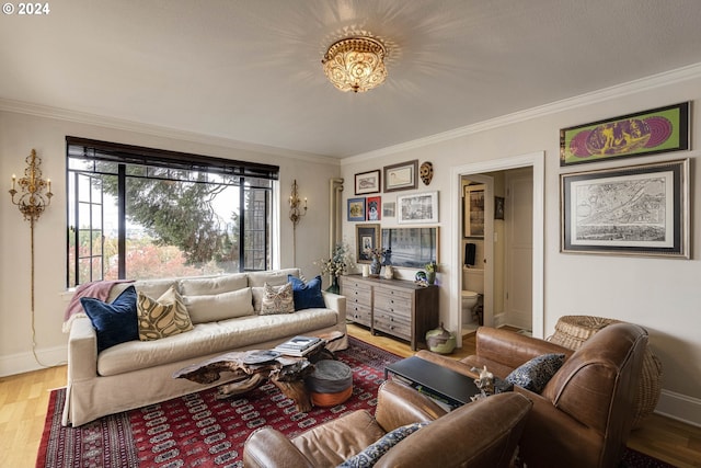 living area featuring light wood-type flooring, crown molding, and baseboards