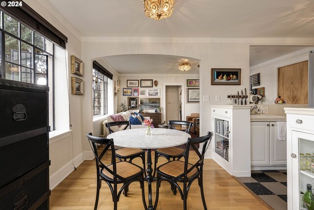 dining space featuring light wood-type flooring, a wealth of natural light, and crown molding