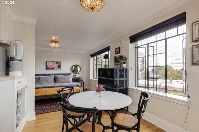 dining room with light wood finished floors, baseboards, and crown molding