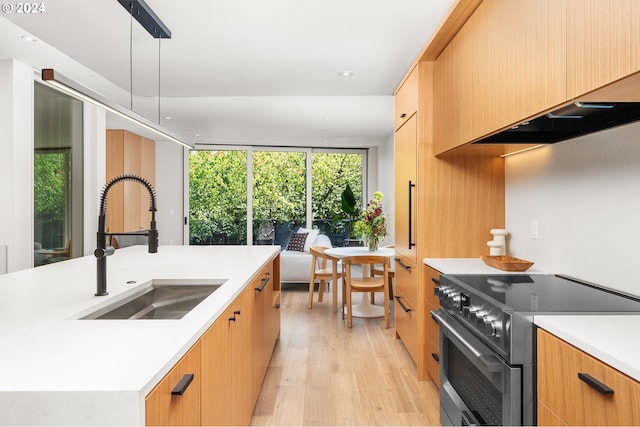 kitchen with a sink, hanging light fixtures, light countertops, stainless steel electric range, and an island with sink