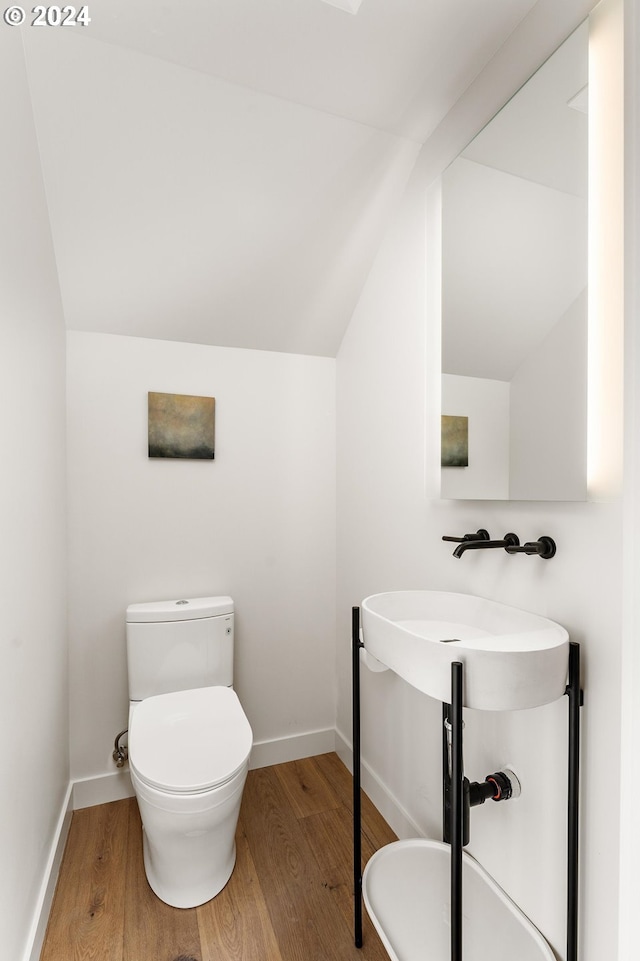 bathroom featuring wood-type flooring, lofted ceiling, and toilet