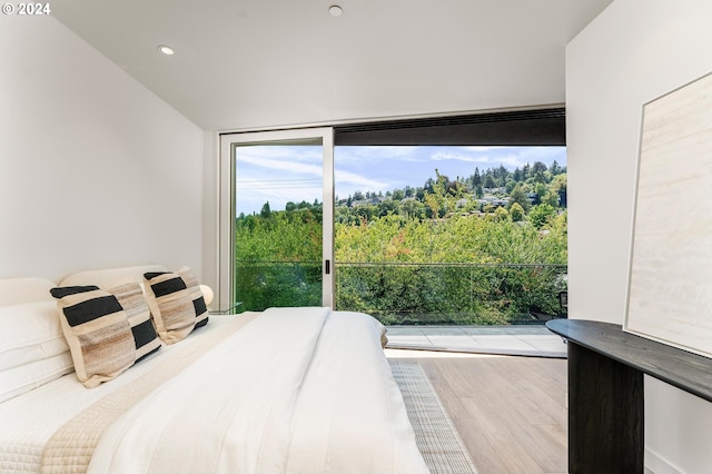 bedroom with a wall of windows, recessed lighting, and light wood-style flooring