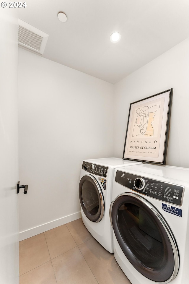 clothes washing area featuring laundry area, light tile patterned floors, baseboards, visible vents, and washer and clothes dryer