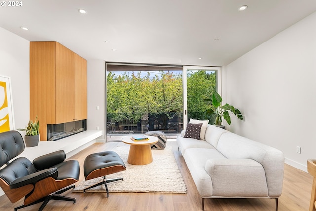 sitting room with expansive windows, a large fireplace, light wood-type flooring, and recessed lighting