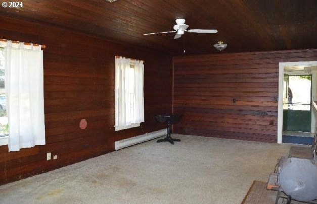 carpeted spare room with wooden walls, ceiling fan, and wooden ceiling