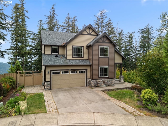 view of front of property featuring an attached garage, fence, stone siding, and driveway