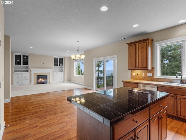 kitchen with light hardwood / wood-style flooring, a center island, a chandelier, and sink