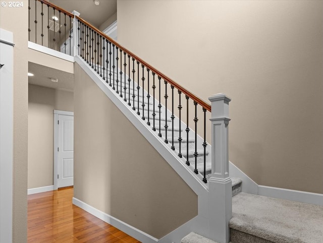 stairway with a high ceiling and hardwood / wood-style flooring